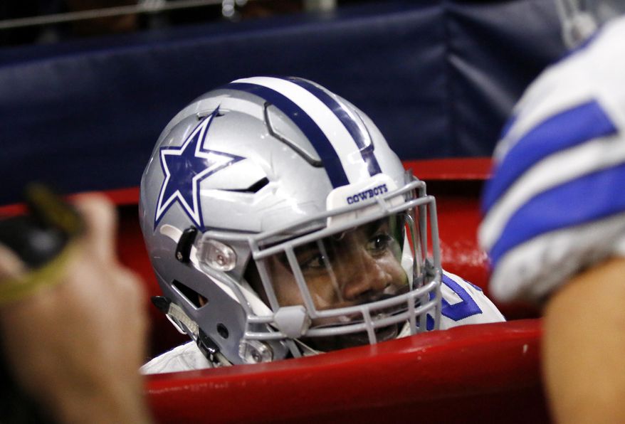 Dallas Cowboys running back Ezekiel Elliott peeks out of a large Salvation Army kettle after jumping into it celebrating a touchdown he scored on a running play in the first half of an NFL football game against the Tampa Bay Buccaneers on Sunday, Dec. 18, 2016, in Arlington, Texas. (AP Photo/Roger Steinman)