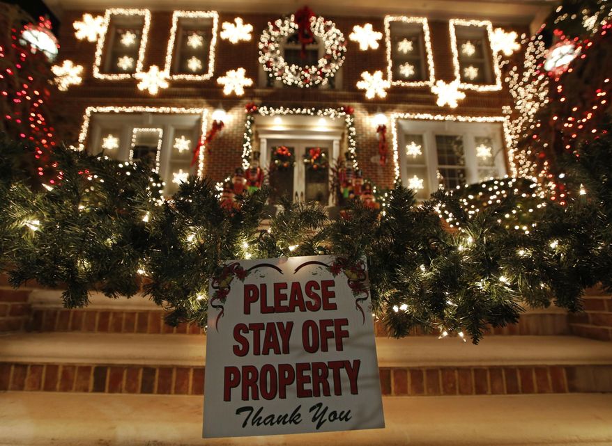 In this Dec. 14, 2016, photo, a sign in front of a decorated house warns visitors to keep off the premises in the Dyker Heights neighborhood of New York. While many residents welcome the crowds that flock to the area to see over-the-top Christmas decorations on private homes, not all residents are happy with the hordes of tourists. (AP Photo/Kathy Willens)