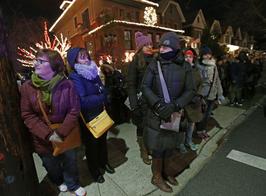 In this Dec. 14, 2016, photo, bundled-up tourists from a "Tour America" group glance around the Dyker Heights neighborhood in Brooklyn Borough of New York after arriving by giant tour bus from midtown Manhattan. In recent years the number of people flooding into the neighborhood has grown exponentially as more and more tourists learn about the area's elaborate Christmas decorations. (AP Photo/Kathy Willens)