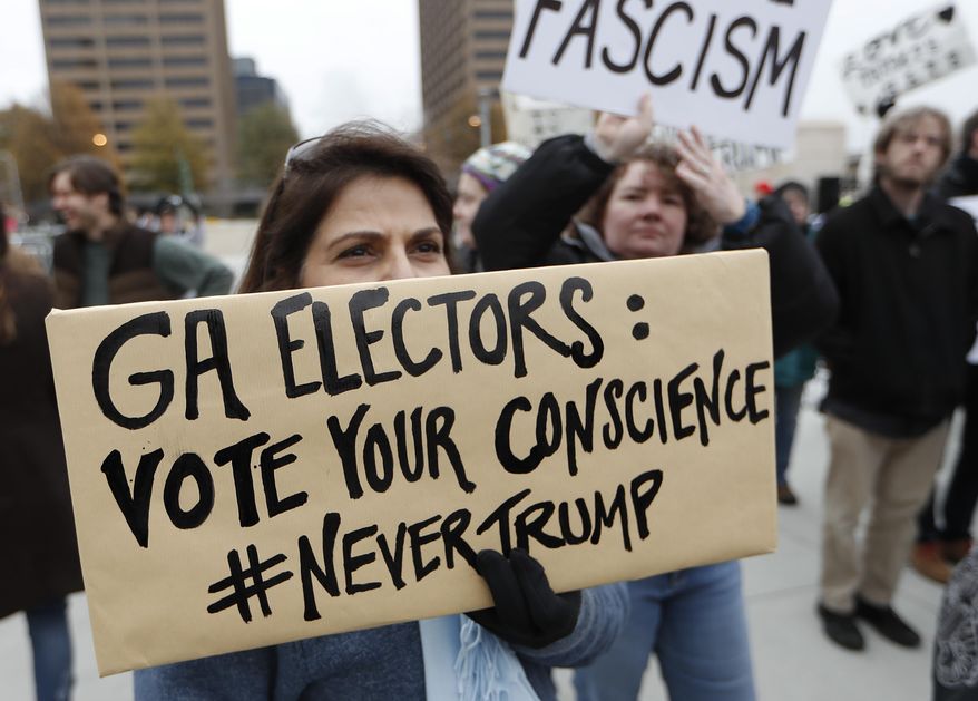 Protesters hold sign outside the Georgia capitol building after electors voted for Donald Trump Monday, Dec. 19, 2016, in Atlanta. (AP Photo/John Bazemore)