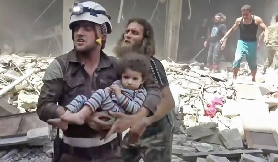 A civil defense worker carries a child after airstrikes hit Aleppo, Syria. (Associated Press)