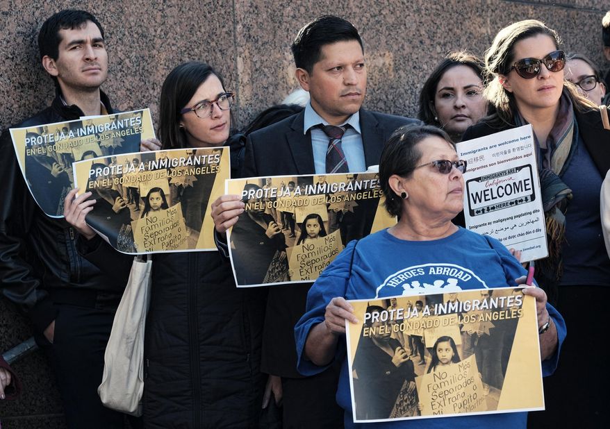 Holding signs that read "Protect Immigrants" pro-immigration demonstrators stand on the steps of the Kenneth Hahn Hall of Administration in downtown Los Angeles on Tuesday, Dec. 20, 2016. The county will consider allocating $3 million to provide lawyers to immigrants following fears of increased deportations under President-elect Donald Trump. The money would form part of a $10 million fund comprised of city, county and private foundation resources. (AP Photo/Richard Vogel)