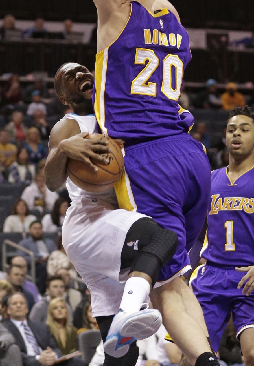 Charlotte Hornets' Kemba Walker, left, is fouled by Los Angeles Lakers' Timofey Mozgov during the first half of an NBA basketball game in Charlotte, N.C., Tuesday, Dec. 20, 2016. (AP Photo/Chuck Burton)