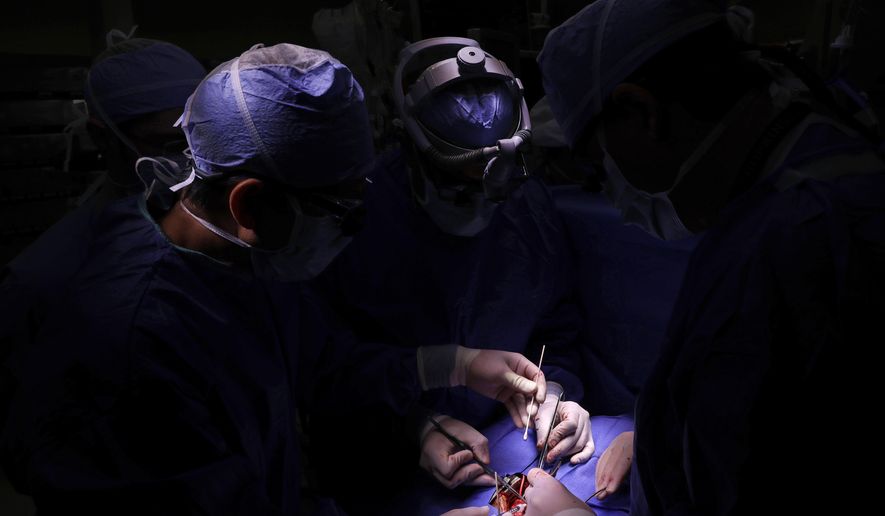 In this Nov. 28, 2016 photo, Dr. Si Pham, left, injects stem cells into Josue Salinas Salgado alongside Dr. Sunjay Kaushal, center, during open heart surgery at the University of Maryland Medical Center in Baltimore. (AP Photo/Patrick Semansky)