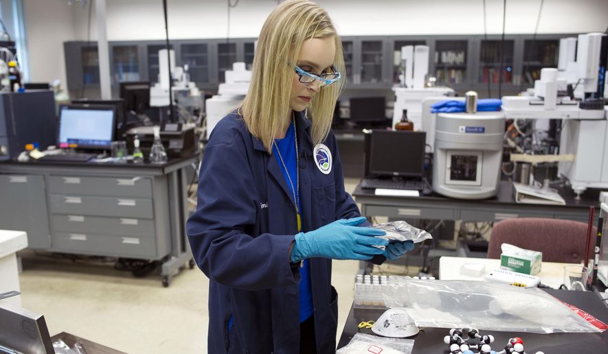 In this Aug. 9, 2016, photo, forensic chemist Emily Dye handles evidence, seized in drug raids, that contains fentanyl analogs at the Drug Enforcement Administration (DEA) Special Testing and Research Laboratory in Sterling, Va. A novel class of deadly drugs is exploding across the country, with many manufactured in China for export around the world. The drugs, synthetic opioids, are fueling the deadliest addiction crisis the U.S. has ever seen. (AP Photo/Cliff Owen)