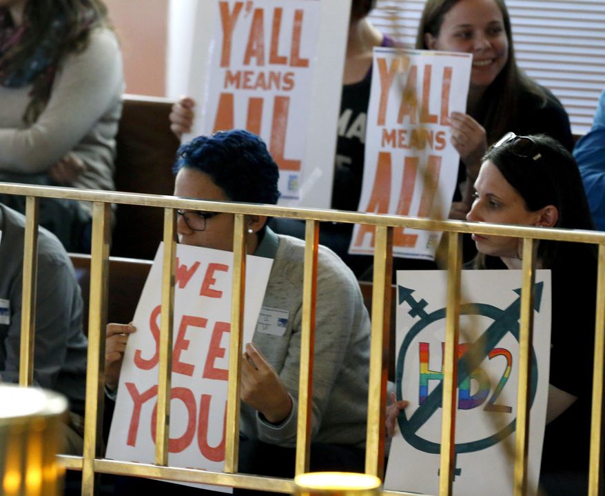 Opponents of HB2 hold signs inside the N.C. Senate chambers gallery as the N.C. General Assembly convenes for a special session at the Legislative Building in Raleigh, N.C., Wednesday, Dec. 21, 2016. (Chris Seward/The News & Observer via AP)