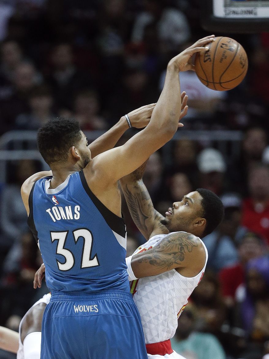 Minnesota Timberwolves center Karl-Anthony Towns (32) passes around Atlanta Hawks defender Kent Bazemore (24) in the first half of an NBA basketball game Wednesday, Dec. 21, 2016, in Atlanta. (AP Photo/John Bazemore)