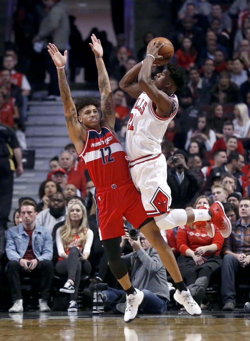 Chicago Bulls' Jimmy Butler, tight, shoots under pressure from Washington Wizards' Kelly Oubre Jr. during the first half of an NBA basketball game Wednesday, Dec. 21, 2016, in Chicago. (AP Photo/Charles Rex Arbogast)