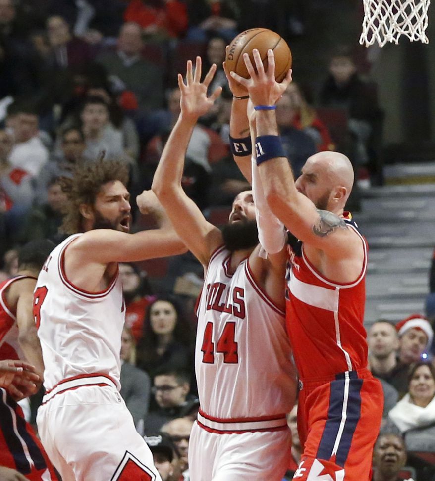 Chicago Bulls' Nikola Mirotic (44) and Washington Wizards' Marcin Gortat, right, battle for a rebound as Robin Lopez watches during the first half of an NBA basketball game Wednesday, Dec. 21, 2016, in Chicago. (AP Photo/Charles Rex Arbogast)