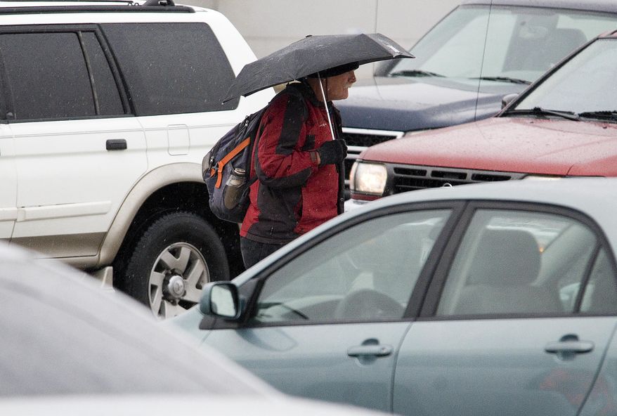 A pedestrian carries an umbrella as he walks past traffic at the intersection of Seventh and La Paz in Victorville, Calif. on Thursday, Dec, 22, 2106. The forecast includes rain and possible snow through Saturday. (James Quigg/The Daily Press via AP)