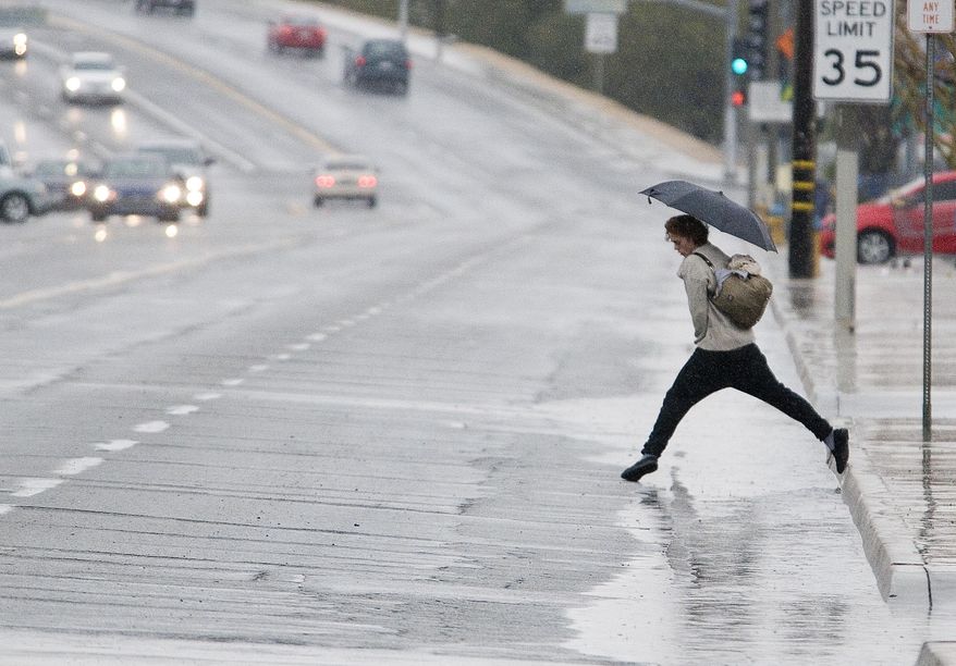 A pedestrian leaps over a puddle along La Paz Road in Victorville, Calif. on Thursday, Dec, 22, 2106. The forecast includes rain and possible snow through Saturday. (James Quigg/The Daily Press via AP)