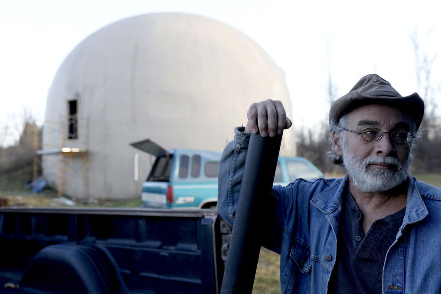 In this Nov. 29, 2016 photo, Wayne Price, 60, holds the blueprints of the 4,650 square feet concrete monolithic dome he was in the processes of building in Otisville, Mich. Financial realities have forced Price to abandon his dream of finishing, and living in, a dome home. Price is selling the unfinished monolithic domed structure for $150,000 after he estimates sinking roughly $200,000 in the project over 16 years (Tegan Johnston/The Flint Journal-MLive.com via AP)