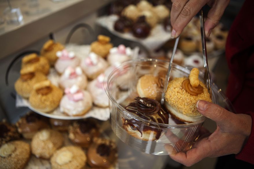 In this Thursday, Dec. 15, 2016 photo, a customer picks doughnuts at a bakery in Bnei Brak, Israel. Israelis are finding new advice hard to swallow: in the name of proper nutrition, their health minister has gone on the warpath against the beloved Hanukkah tradition of gorging on sugar-laden, deep-fried, jam-filled doughnuts. Yaakov Litzman _ the bearded, black-coated chief of a powerful ultra-Orthodox political party _ considers himself a guardian of Jewish traditions. But he also wears another hat, as a health conscious official on a crusade to stamp out junk food and child obesity. (AP Photo/Dan Balilty)