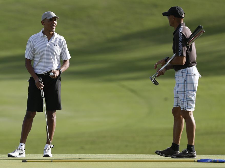 President Barack Obama looks to Darrell Harrington as they golf the 18th green at Kapolei Golf Club, in Kapolei, Hawaii, Wednesday, Dec. 21, 2016. (AP Photo/Carolyn Kaster)