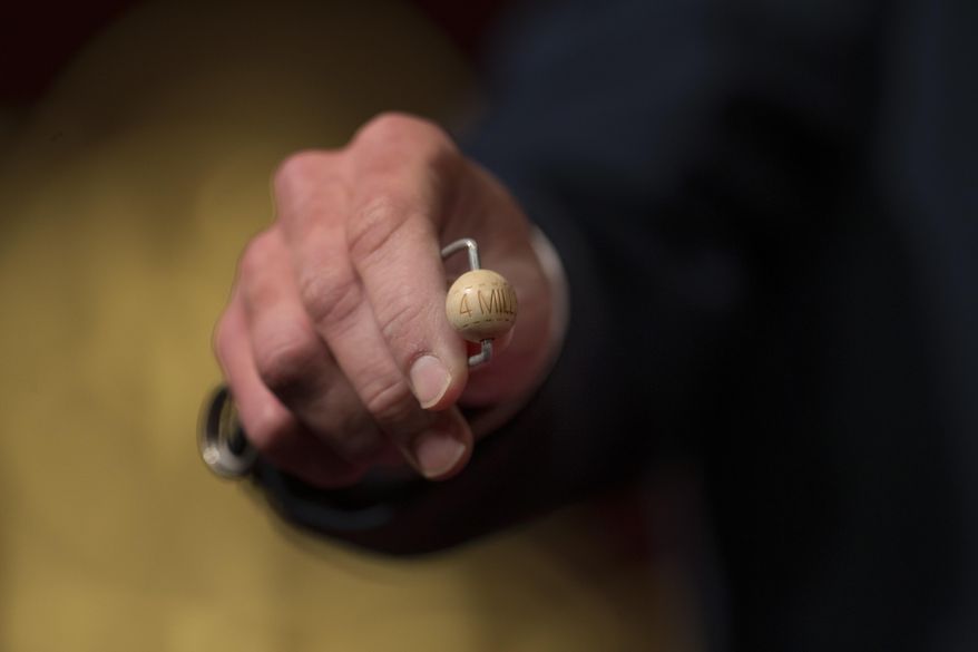 A worker holds out the ball with the top prize of euro 4,000,000 ($4,186,820) during the Spanish Christmas lottery draw, known as 'El Gordo' or 'The Fat One', in Madrid, Thursday, Dec. 22, 2016. (AP Photo/Francisco Seco)
