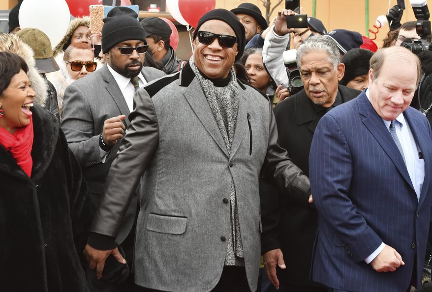Motown legend Stevie Wonder walks down Milwaukee Street, a portion of which will soon be renamed Stevie Wonder Avenue, with Detroit City Council President Brenda Jones, far left, and Detroit Mayor Mike Duggan, far right, during a ceremony in Detroit on Wednesday, Dec. 21, 2016. (The Detroit News/ Daniel Mears/Detroit News via AP)