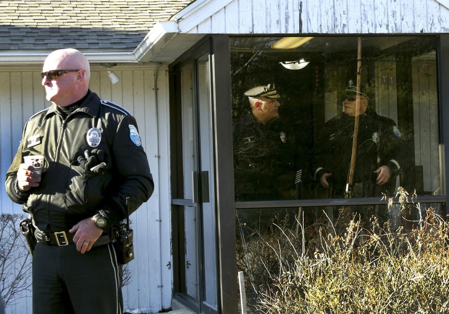 In this Tuesday, Dec. 20, 2016 photo Charlestown, R.I. patrol officer Kevin Ryan, left, stands outside an entrance to the Narragansett tribe's administration building in Charlestown after a faction of the tribe took over the building. Members of a recently elected Narragansett Tribal Council said they took over the administration building Tuesday, Dec. 20 because Chief Sachem Matthew Thomas has refused to relinquish power after they impeached him in October. (Harold Hanka/The Sun via AP)