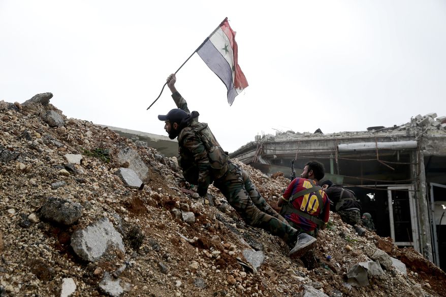 A Syrian army soldier places a Syrian national flag during a battle with rebel fighters at the Ramouseh front line, east of Aleppo, Syria, Monday, Dec. 5, 2016. (AP Photo/Hassan Ammar, File)
