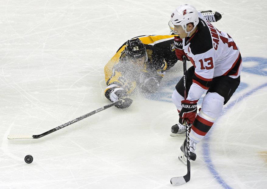 Pittsburgh Penguins left wing Carl Hagelin (62) tries to play the puck away from New Jersey Devils left wing Michael Cammalleri (13) during the first period of an NHL hockey game Friday, Dec. 23, 2016, in Pittsburgh. (AP Photo/Fred Vuich)