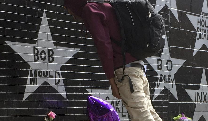 ADVANCE FOR USE SATURDAY, DEC. 24 - FILE - In this April 21, 2016 file photo, Terrance May, a musician who goes by the name May Millions, takes a moment at a growing memorial outside First Avenue, a Minneapolis club where Prince filmed a large portion of his classic movie "Purple Rain" and recorded several songs on the accompanying album in Minneapolis. Prince joined the sad parade of celebrity musicians like David Bowie, Merle Haggard and Leonard Cohen who died in 2016. The body of the Oscar and seven-time Grammy winner was found at his sprawling Paisley Park recording complex in suburban Minneapolis on April 21. He was 57. (AP Photo/Kevin Burbach, File)
