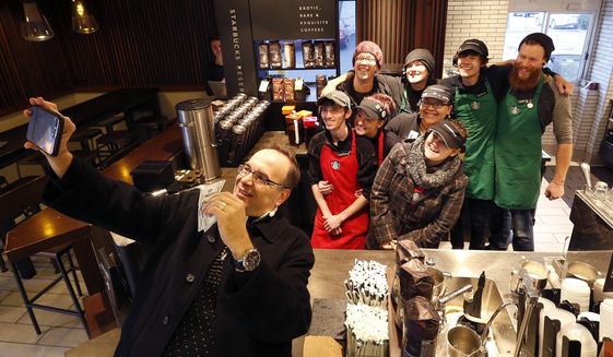 In this Dec. 19, 2016 photo, Father Jim Sichko takes a selfie with employees after giving them each a $100 bill at Starbucks, in Lexington, Ky. Sichko paid out about $6,000 in holiday good will to a Starbucks counter crew, a Muslim refugee family, a Hispanic family with a desperately ill father and an LGBT man who needed help with groceries for himself and his mother. (Charles Bertram/Lexington Herald-Leader via AP)