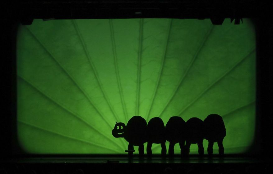 In this photo taken on Tuesday, Dec. 20, 2016, dancers of the U.S. company 'Catapult' create a caterpillar, during their show 'Magic Shadows', in Milan, Italy. Dancers in the company create shadow sculptures with their bodies, giving a contemporary twist to the ancient Chinese art of shadow theaters. (AP Photo/Luca Bruno)