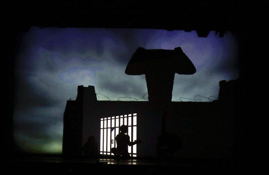 In this photo taken on Tuesday, Dec. 20, 2016, dancers of the U.S. company 'Catapult' create a jail, during their show 'Magic Shadows', in Milan, Italy. Dancers in the company create shadow sculptures with their bodies, giving a contemporary twist to the ancient Chinese art of shadow theaters. (AP Photo/Luca Bruno)