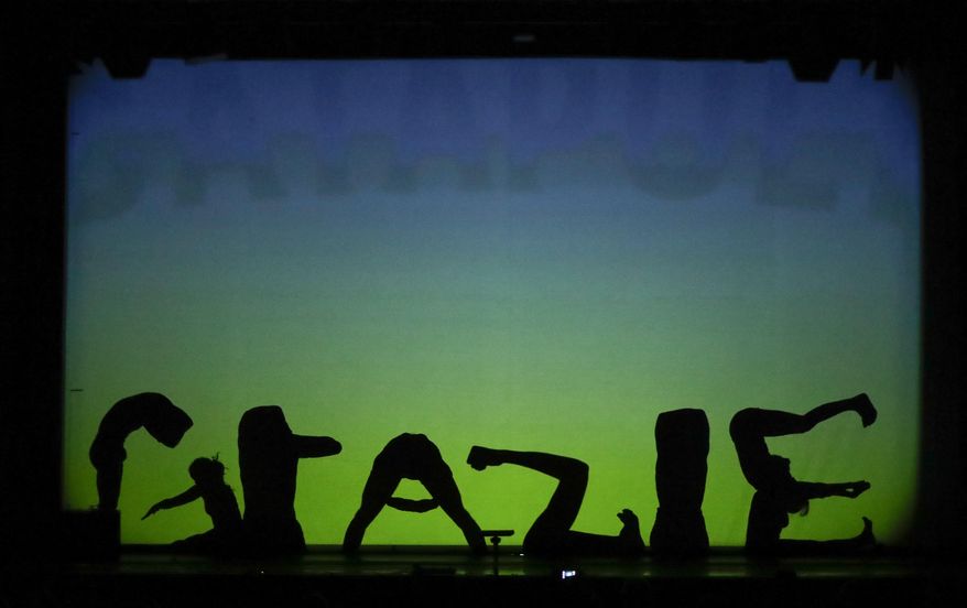 In this photo taken on Tuesday, Dec. 20, 2016, dancers of the U.S. company 'Catapult' create the Italian word 'Grazie' (Thank you) at the end of their show 'Magic Shadows', in Milan, Italy. Dancers in the company create shadow sculptures with their bodies, giving a contemporary twist to the ancient Chinese art of shadow theaters. (AP Photo/Luca Bruno)