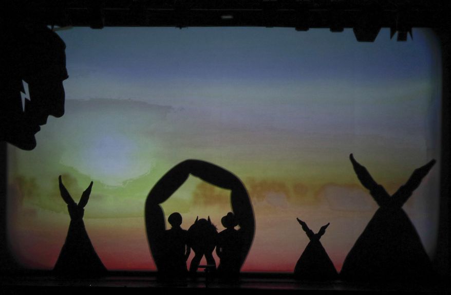 In this photo taken on Tuesday, Dec. 20, 2016, dancers of the U.S. company 'Catapult' create an Indian camp, during their show 'Magic Shadows', in Milan, Italy. Dancers in the company create shadow sculptures with their bodies, giving a contemporary twist to the ancient Chinese art of shadow theaters. (AP Photo/Luca Bruno)