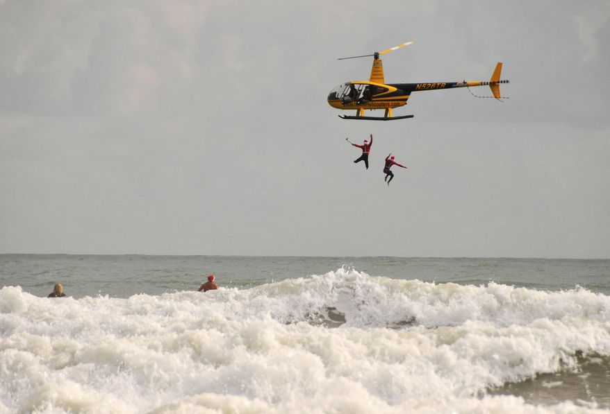 People dressed as Santa jump from a helicopter during a surfing Santa event in Cocoa Beach, Fla., Saturday, Dec. 24, 2016. The Christmas event supports Grind for Life and the Surf Museum. (Malcolm Denemark/Florida Today via AP)