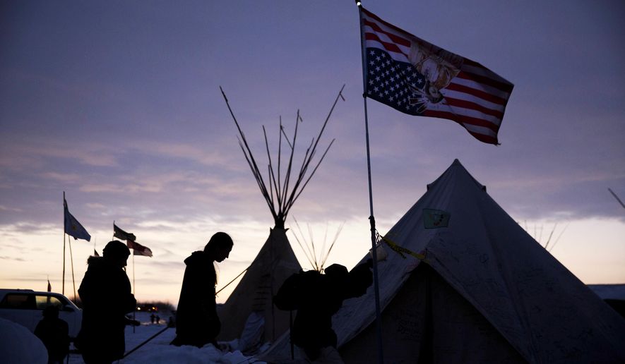 Travelers arrive at the Oceti Sakowin camp where people have gathered to protest the Dakota Access oil pipeline as they walk into a tent next to an upside-down american flag in Cannon Ball, N.D., in this Dec. 4, 2016, file photo. (AP Photo/David Goldman File)