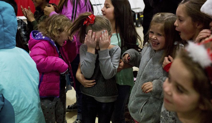 In this Dec. 21, 2016 photo, children react to the kiss after an engagement during a Christmas event at the Spanish Fork Airport in Spanish Fork, Utah. This year Santa brought toys for all the children as well as a very special gift for one couple. (Sammy Jo Hester/The Daily Herald via AP)