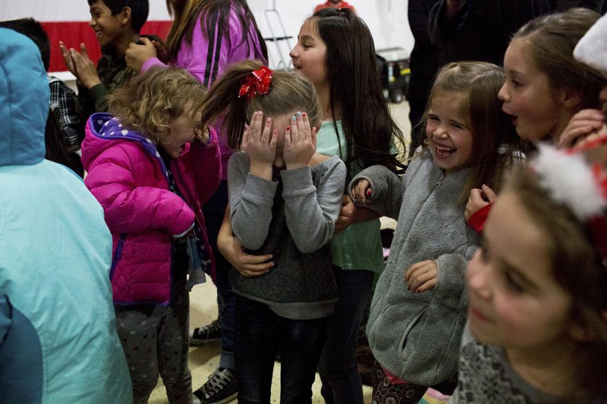 In this Dec. 21, 2016 photo, children react to the kiss after an engagement during a Christmas event at the Spanish Fork Airport in Spanish Fork, Utah. This year Santa brought toys for all the children as well as a very special gift for one couple. (Sammy Jo Hester/The Daily Herald via AP)