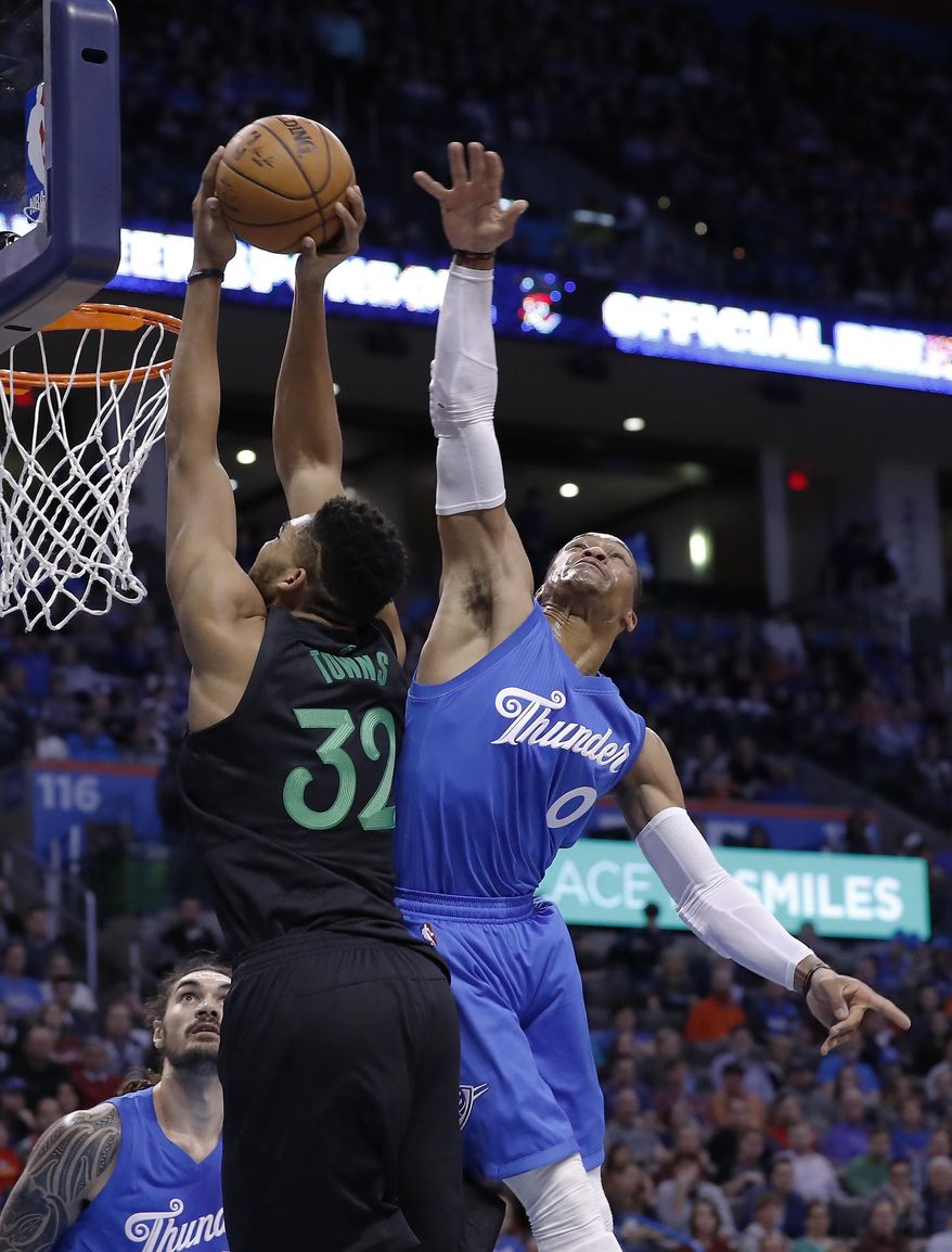 Minnesota Timberwolves center Karl-Anthony Towns (32) goes to the basket as Oklahoma City Thunder guard Russell Westbrook (0) defends during the first half of an NBA basketball game in Oklahoma City, Sunday, Dec. 25, 2016. (AP Photo/Alonzo Adams)