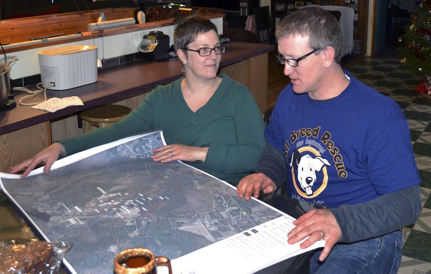 In this Friday, Dec. 16, 2016 photo, Debbie and Richard Higgins, whose well water has been contaminated by a suspected carcinogen from a Dartmouth dump site, look at a map on their kitchen table in Hanover, N.H., which shows where the contamination has spread. Dartmouth College said it has spent around $8.4 million cleaning up contamination where scientists dumped carcasses of lab animals in the 1960s and 1970s. (AP Photo/Michael Casey)