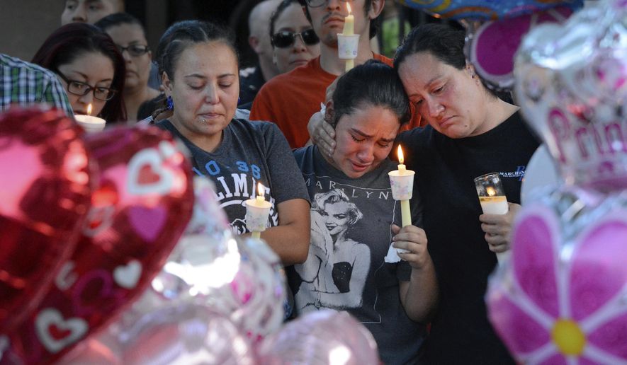 FILE - In this Thursday Aug. 25, 2016, file photo, from left to right, Nicole Maldonado, Myriah Flores and her mother Sharlene Benavidez attend a candlelight vigil for Victoria Martens at the apartment complex, in Albuquerque, N.M., where the young girl lived and was killed. The brutality of Victoria’s slaying sent shockwaves through New Mexico in August, but it marked only one of a handful of heartbreaking cases involving children in 2016. (Jim Thompson/The Albuquerque Journal via AP, File)