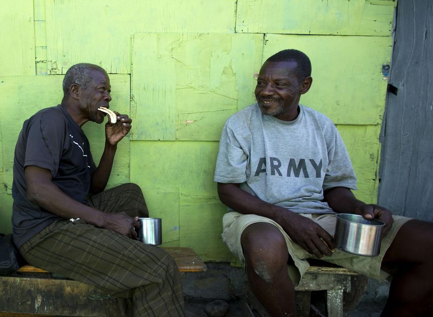 In this Dec. 25, 2016 photo, "bayakou", or human waste cleaner, Auguste Augustin, left, visits with a friend in Port-au-Prince's La Saline slum, Haiti. Augustin has no shame talking about his labor. He's been doing it for decades and says he's proud his hard work feeds his family. (AP Photo/Dieu Nalio Chery)