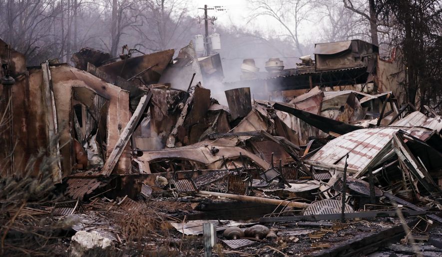FILE -In this Wednesday, Nov. 30, 2016 file photo, smokes rises out of the remains of a burned-out business, in Gatlinburg, Tenn., after a wildfire swept through the area Monday. Wildfires ravaged the tourist town of Gatlinburg, in the shadow of the Great Smoky Mountains, killing 14 people, destroying businesses and leaving hundreds of people homeless just after Thanksgiving. The devastation was voted Tennessee’s top for 2016 in a poll of Associated Press editors and broadcasters, followed by the Nov. 21 school bus crash in Chattanooga that left six elementary school children dead. (AP Photo/Mark Humphrey, File)