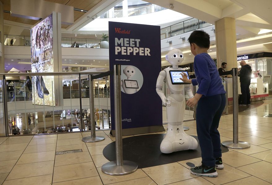 In this Thursday, Dec. 22, 2016, photo, a boy plays with Pepper the robot at Westfield Mall in San Francisco. While merrily chirping, dancing and posing for selfies, Pepper looks like another expensive toy in the San Francisco mall where it will be entertaining shoppers through mid-February. But it would be a mistake to dismiss Pepper as mere child's play, even though kids flock around the 4-foot-tall humanoid as it speaks in a cherubic voice that could belong to either a boy or girl. (AP Photo/Jeff Chiu)