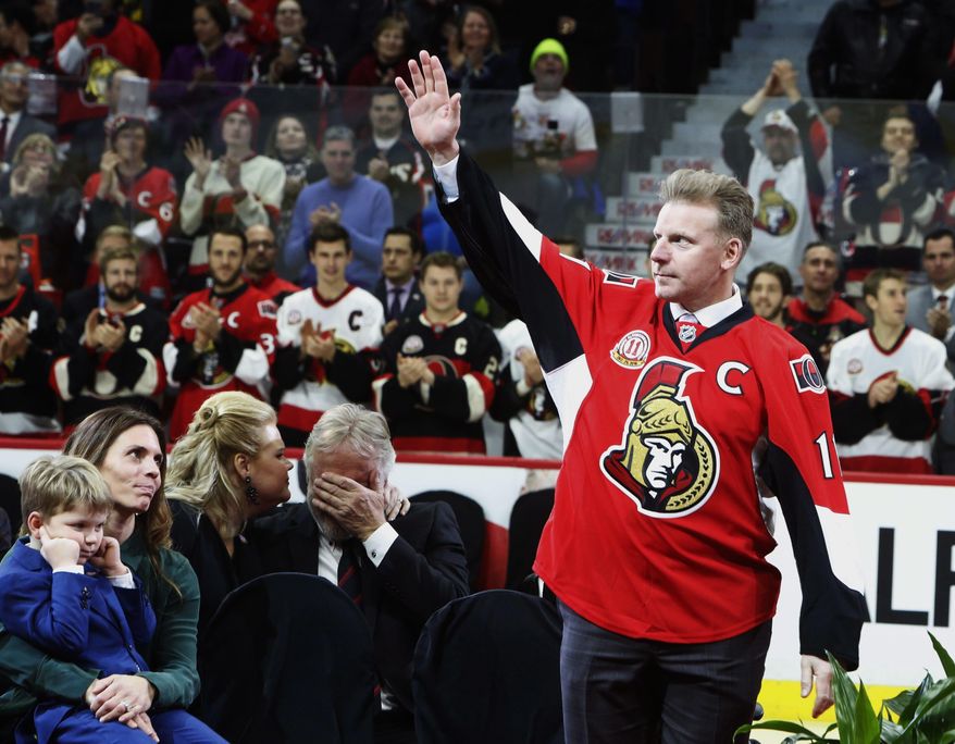 Former Ottawa Senators player Daniel Alfredsson makes his way to the ice as his father Hasse Alfredsson, center, is comforted by his daughter Cecelia Sable as Alfredsson's wife Birgitta and son Fenix look on during a ceremony retiring Alfredsson's Senators jersey number 11 in Ottawa, Ontario, Thursday Dec. 29, 2016. (Fred Chartrand/The Canadian Press via AP)