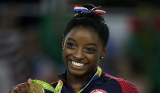 In this Aug. 16, 2016, file photo, United States&#39; Simone Biles displays her gold medal for the floor routine during the artistic gymnastics women&#39;s apparatus final at the 2016 Summer Olympics in Rio de Janeiro, Brazil. (AP Photo/Rebecca Blackwell, File)