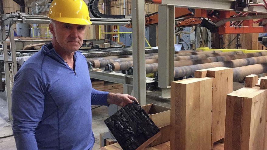 In this Nov. 11, 2016 photo, John Redfield, chief operating officer of D.R. Johnson Lumber Co. in Riddle, Ore., poses for a photo as he shows an example of a cross-laminated timber, or CLT, panel that underwent a flammability test. D.R. Johnson is one of just two companies in the United States currently able to produce CLT panels. (AP Photo/Gillian Flaccus)