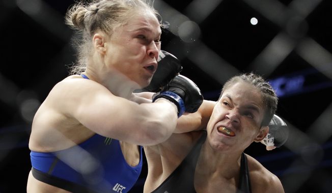 Amanda Nunes, right, connects with Ronda Rousey in the first round of their women&#x27;s bantamweight championship mixed martial arts bout at UFC 207, Friday, Dec. 30, 2016, in Las Vegas. Nunes won the fight after it was stopped in the first round. (AP Photo/John Locher)