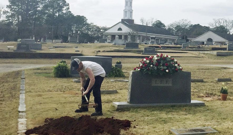 ADVANCE FOR WEEKEND EDITIONS - FILE - In this Saturday, Feb. 20, 2016, file photo, a man rakes soil over a grave in the Lee family cemetery plot, in Monroeville, Ala. Harper Lee, the author of "To Kill a Mockingbird," died Friday, Feb. 19. Literary icon Harper Lee died in February at age of 89. Lee had stunned the world a year earlier when her publisher announced that a second novel "Go Set a Watchman" would be published. Lee was buried in a quiet service in Monroeville with only a few select friends and family present, a reflection of how the famously private author had lived her life. (AP Photo/Kim Chandler, File)