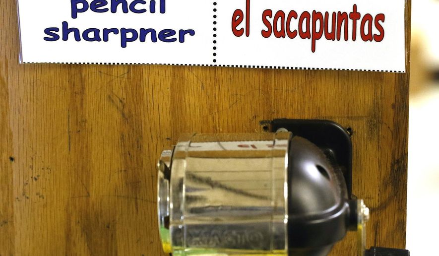 FILE - In this Aug. 24, 2016 photo, bilingual teacher Abraham Robledo labels items in his classroom for his first graders at James S. Hogg Elementary School in Dallas. While Californians passed a ballot measure to bring back bilingual education in the upcoming school year, educators say a challenge to getting the programs started will be getting more bilingual teachers. Nearly two decades after banning most bilingual education, Californians voted in November to let schools restore it for English learners and English speakers whose parents want them to learn Spanish, Mandarin and other languages to complete globally for jobs. (David Woo/The Dallas Morning News via AP, File)