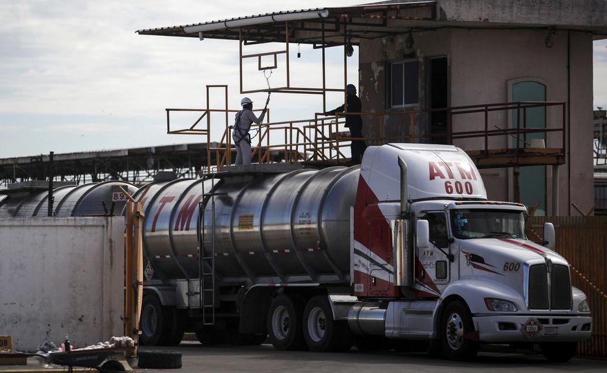 Workers inspect a tanker truck inside the storage and dispatch terminal of Petroleos Mexicanos (PEMEX), Mexico's state-owned oil company, in the port of Veracruz, Mexico, Dec. 30, 2016, days before the deregulation of gas prices. Many Mexicans are skeptical that capitalism is a good thing for the energy sector, which was nationalized in 1938 and has long been considered part of the national patrimony, while opposition politicians on the left have lent support to calls for protests against the deregulation. (AP Photo/Felix Marquez)