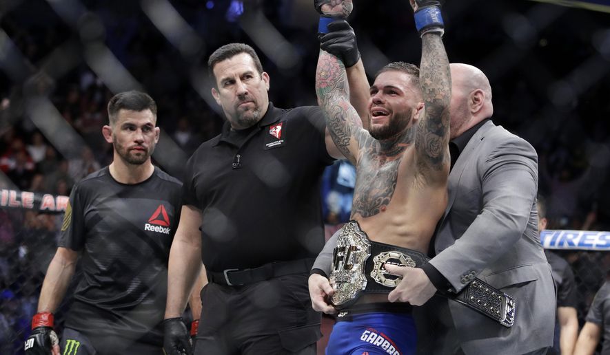 Cody Garbrandt, right, celebrates as he receives his belt after defeating Dominick Cruz, left, in a bantamweight championship mixed martial arts bout at UFC 207, Friday, Dec. 30, 2016, in Las Vegas. Garbrandt won by unanimous decision. (AP Photo/John Locher)