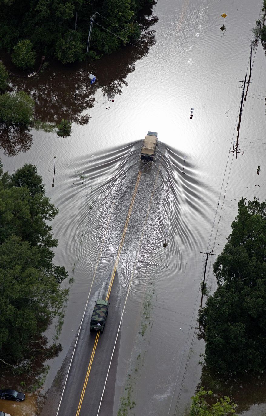 ADVANCE FOR WEEKEND EDITIONS - FILE - In this Aug. 13, 2016 aerial file photo over Robert, La., Army National Guard vehicles drive on flooded U.S. Route 190 in Robert, La., after heavy rains inundated the region. Louisiana Gov. John Bel Edwards says more than 1,000 people in south Louisiana have been rescued from homes, vehicles and even clinging to trees as a slow-moving storm hammers the state with flooding. (AP Photo/Max Becherer, File)
