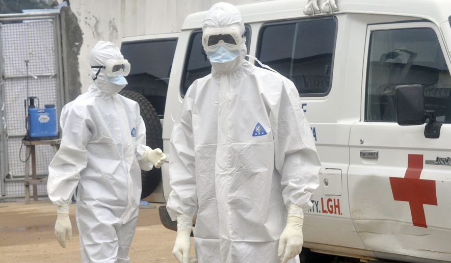 Health workers wearing protective gear wait to carry the body of a person suspected to have died from Ebola in Monrovia, Liberia, on Oct. 13, 2014. (Associated Press)