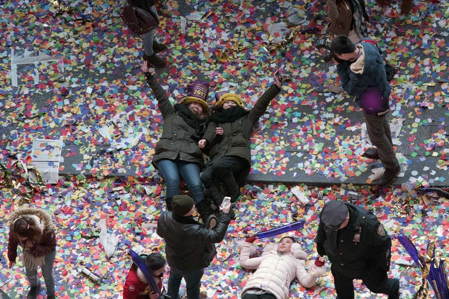 Revelers pose for a photo lying in the confetti during the new year celebration in New York's Times Square as seen from the Marriott Marquis, Sunday, Jan. 1, 2017. (AP Photo/Mary Altaffer)